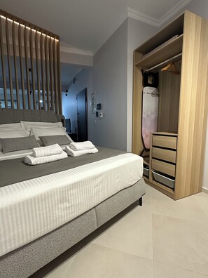 A modern bedroom with a large bed, a wooden wardrobe, and a built-in bench. - The Hidden Courtyart Studio | Dedicated Outdoor Area | Sleeps 3 (Vironas)