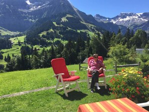 A person seated on a red chair with a view of a mountainous landscape. - Im Rägeboge Appartement/Fewo, Dusche, WC, 1 Schlafraum by Interhome (Adelboden)