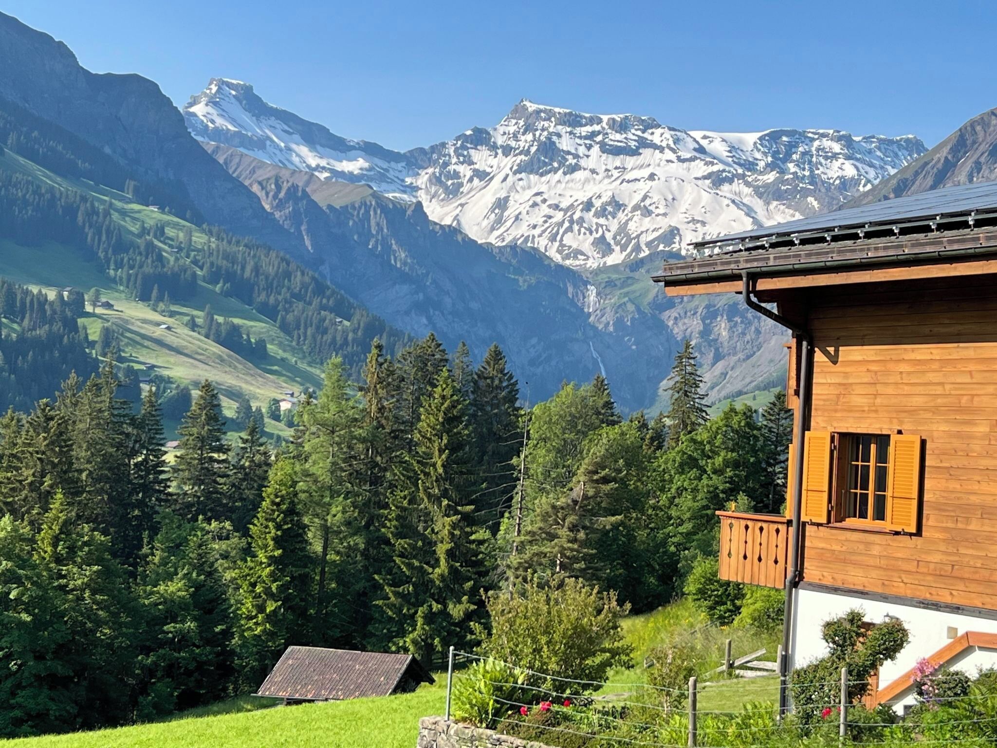 Un chalet en bois doté d’un balcon donnant sur un paysage montagneux aux sommets enneigés.