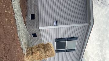 A two-story building with a grey roof, a brick foundation, and a number '968' sign on the side.