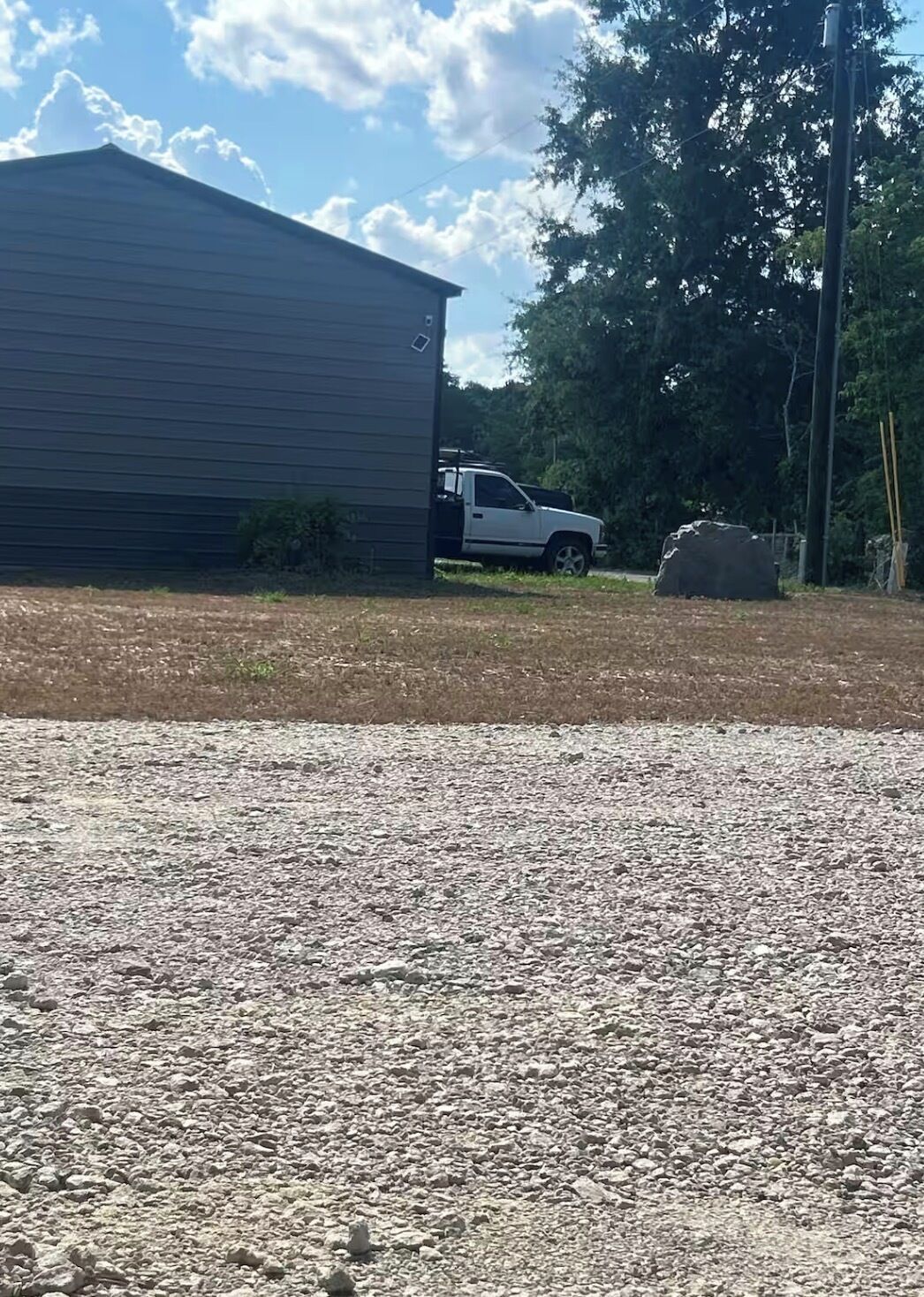 A gravel driveway leading to a building with a parked truck.