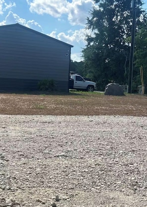 A gravel driveway leading to a building with a parked truck. - Tent in Leland perfect for your outdoor getaway (Leland)