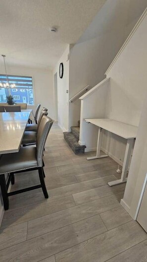 Un espace repas avec une longue table et des chaises, un escalier et une vue sur l’extérieur.
