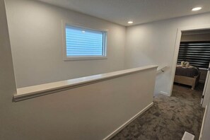 A narrow hallway with a window and a door leading to a bedroom.