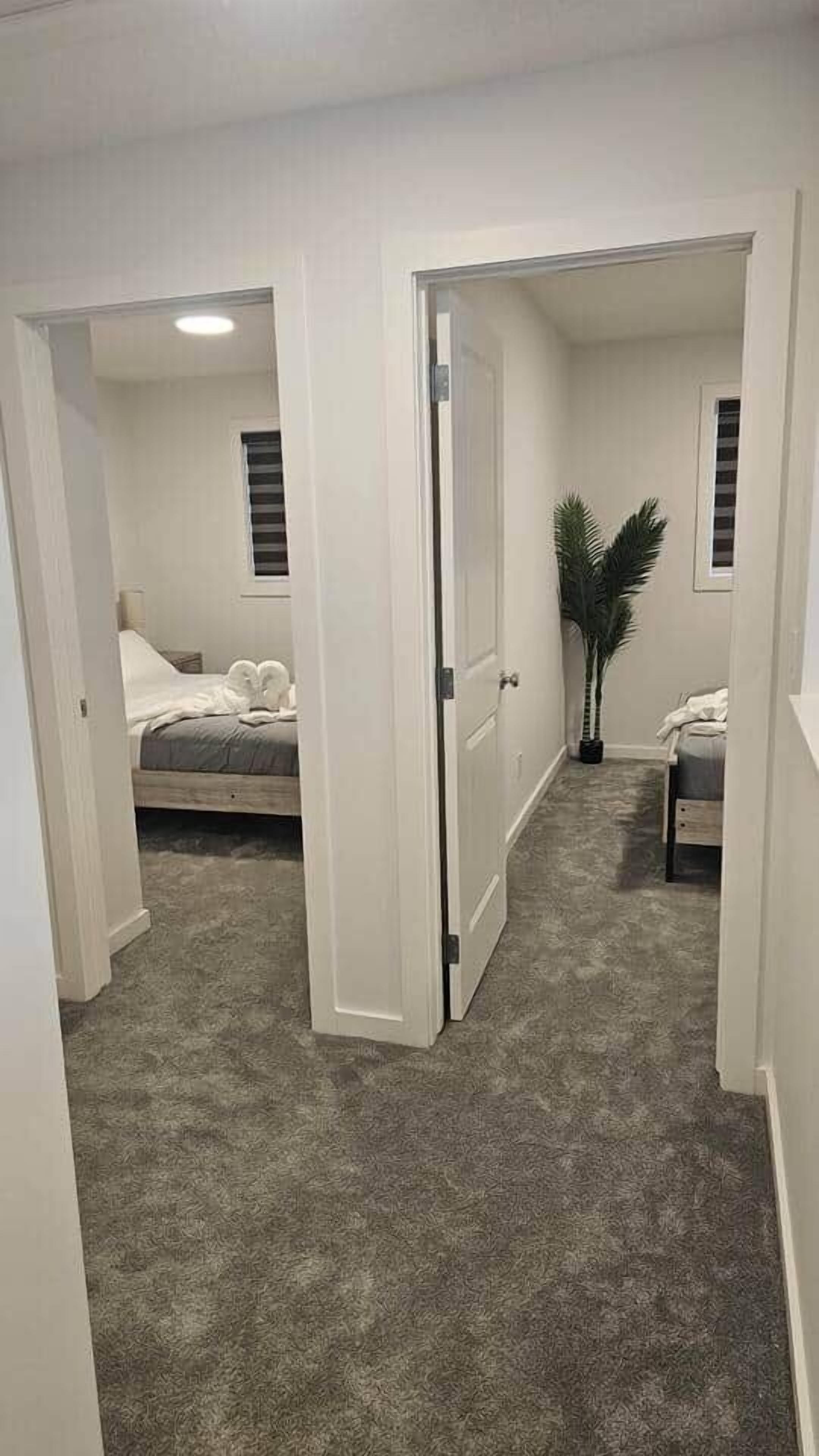 Quarto com cama, mesa de cabeceira, planta em vaso e janela com persianas.