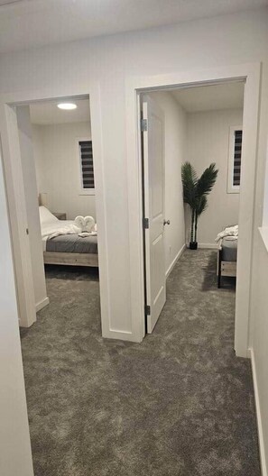 Une chambre à coucher avec un lit, une table de chevet, une plante en pot et une fenêtre avec des stores.