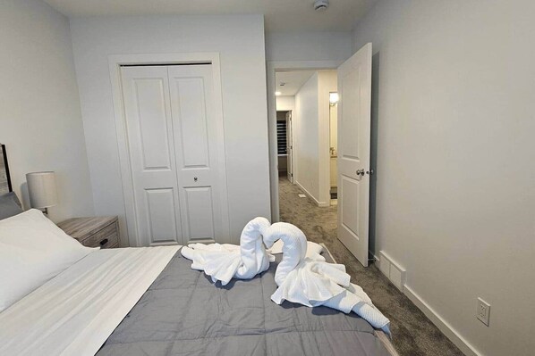 A hotel room with a bed, a nightstand, a lamp, and a door leading to a hallway.