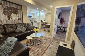 A modern living room with a leather sofa, a coffee table, and a world map wall. - Luxury suite with 2-bedroom and 2 beds + Free Wifi (Calgary)