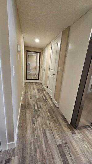 A hallway with a wooden floor, white walls, and a door at the end. - Luxury suite with 2-bedroom and 2 beds + Free Wifi (Calgary)