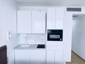 A modern kitchen with white cabinetry, a built-in microwave, and a sink. - Blue Elegant Suite (Thessaloniki)