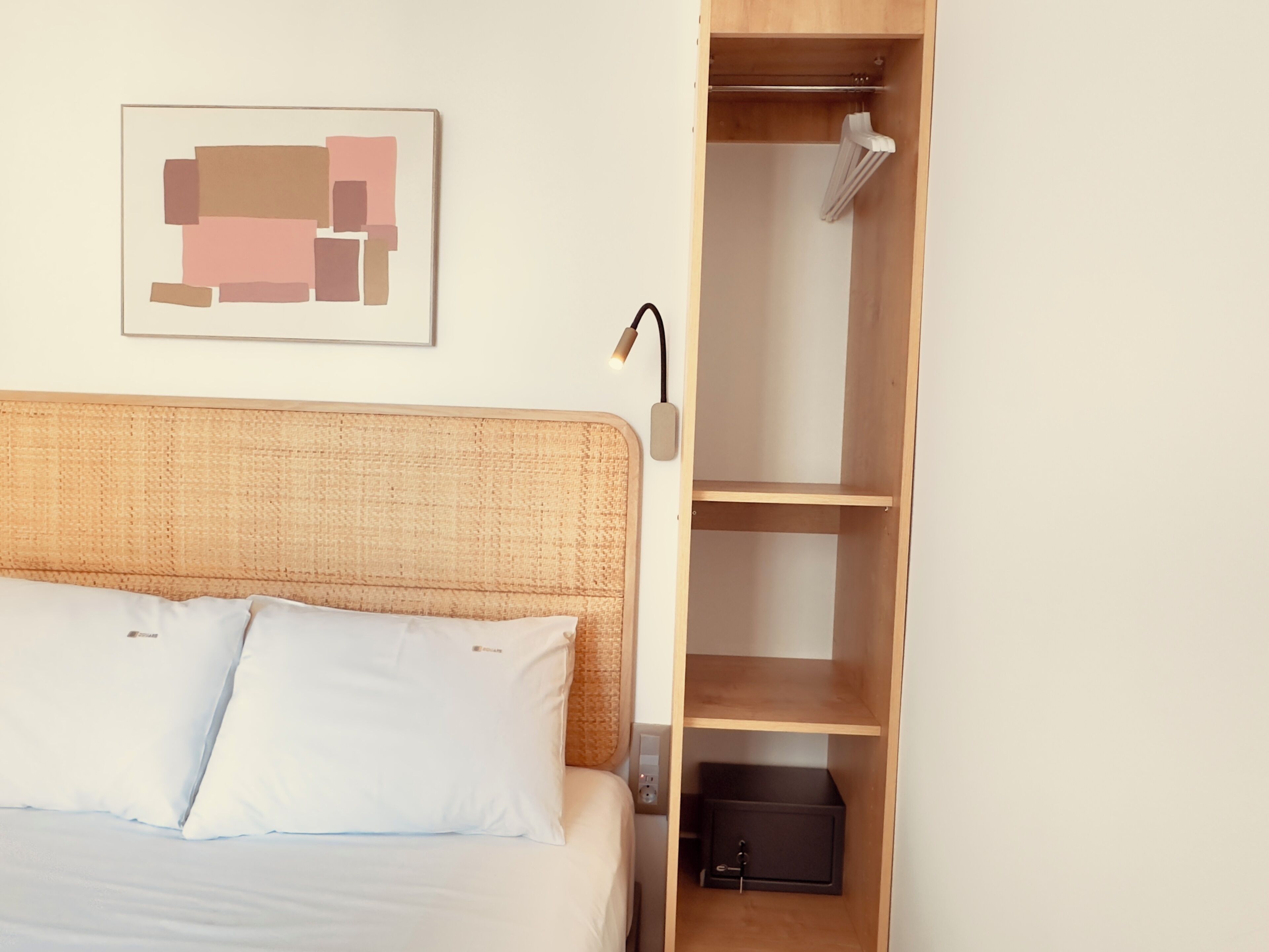 Une chambre à coucher comprenant un lit, une table de chevet, une lampe, une armoire et un tableau accroché au mur.