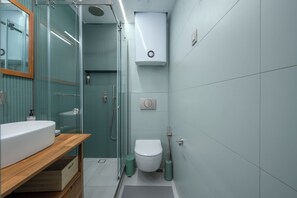 A modern bathroom with a glass shower enclosure, a white toilet, and a wooden vanity with a sink. - Blue Elegant Suite (Thessaloniki)