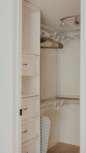 Ein begehbarer Kleiderschrank mit offenen Regalen, einer Kleiderstange und einem Schuhregal.