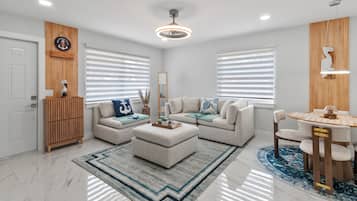 A modern living room with a sofa set, a coffee table, and a dining area with a table and chairs.