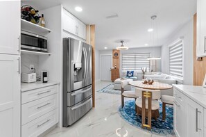 A modern kitchen with a stainless steel refrigerator, built-in microwave, and a coffee machine. - Cozy 2-bedroom house in lovely Naples with private courtyard for relaxing stays. (Naples)