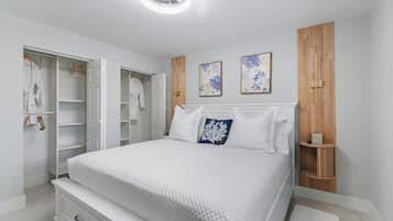 A bedroom with a bed, a wardrobe, and two wall-mounted paintings.