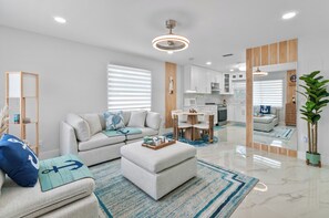 Una sala de estar moderna con un sofá, un reposapiés y un comedor con mesa y sillas.