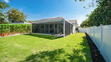 A house with a covered patio area, a fenced yard, and a variety of plants.