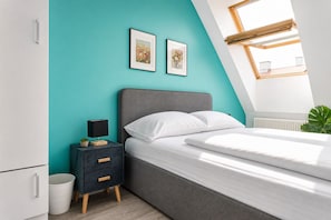 A bedroom with a bed, a nightstand, a wall-mounted shelf, and a window with a view.