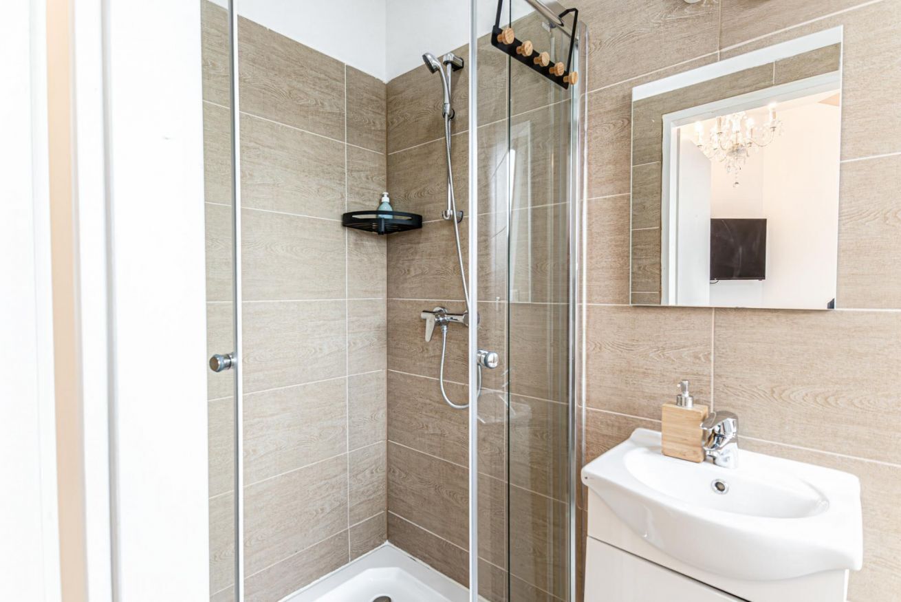 Une salle de bain moderne avec une douche à parois de verre, un lavabo blanc et un miroir.