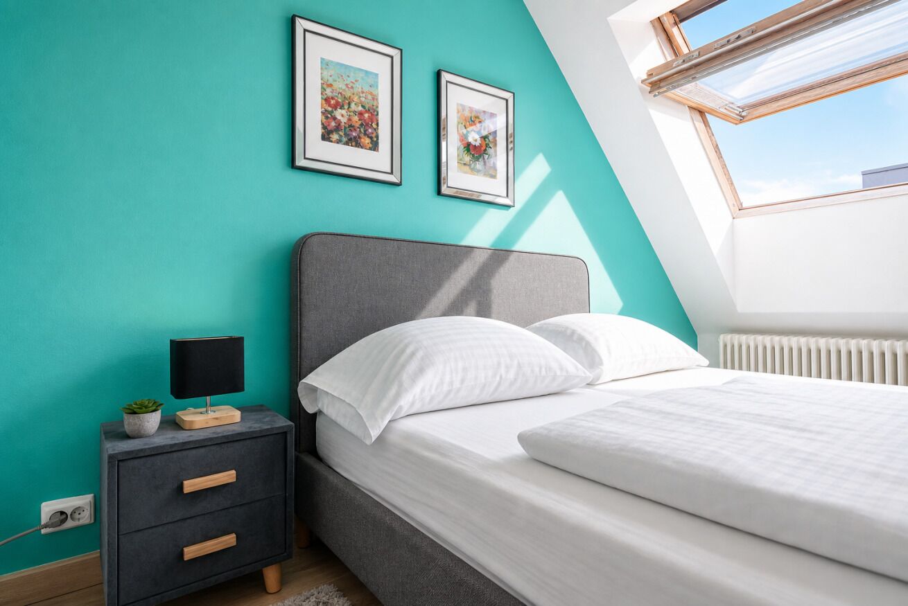 Une chambre à coucher avec un lit, une table de chevet, une lampe et deux tableaux encadrés accrochés au mur.