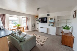 Ein kompakter Wohnraum mit Küchenzeile, Essbereich und einer Sitzecke mit Sofa.