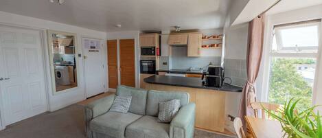 Un espacio habitable compacto con kitchenette, un sofá y vistas al exterior.