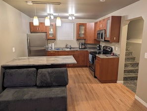 A compact kitchen with wooden cabinets, a refrigerator, a microwave, and a stove.