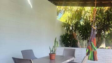 Eine Terrassengaststätte mit Tisch und Stühlen, einem Blumentopf und einer hängenden Dekoration.