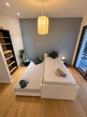 A modern bedroom with two beds, a bedside table with a lamp, a plant, and a bookshelf. - Luxury Villa • Swimming Pool • View • Elevator (Falicon)