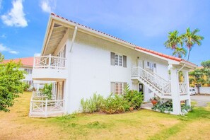A two-story building with a balcony, a staircase, and a red-tiled roof. - Cozy one Bed across from Eatery and Pickle Ball (Kingston 6)