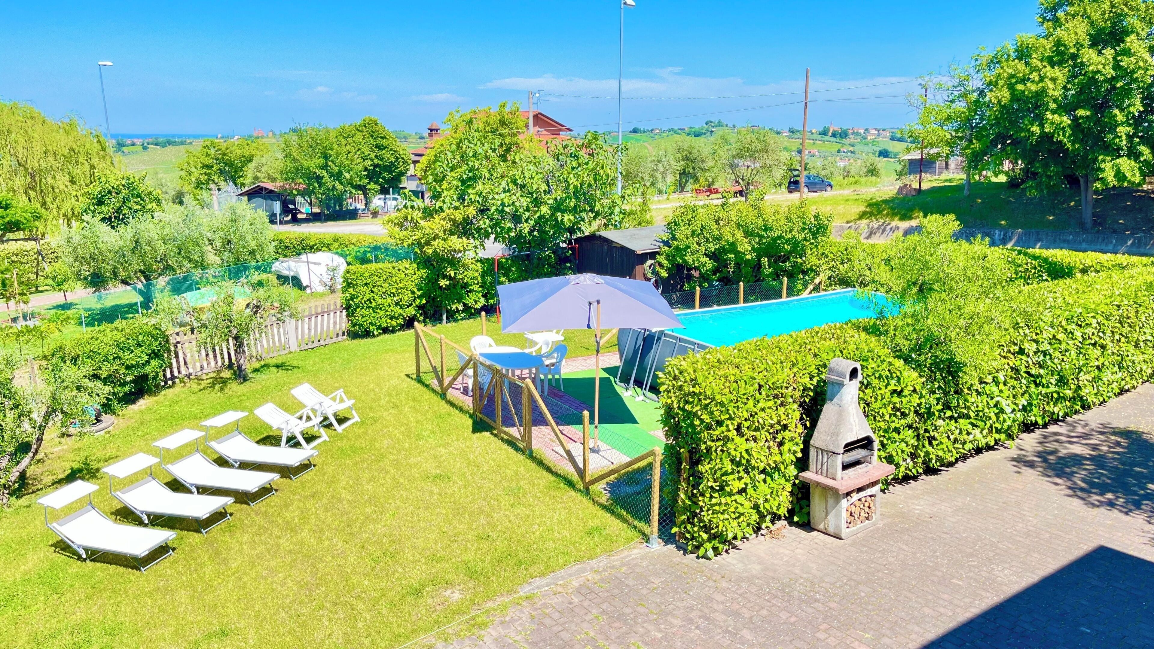 Un quartiere residenziale con piscina, sedie a sdraio e barbecue.