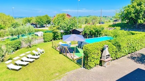 Ett bostadsområde med en swimmingpool, solstolar och en grillplats.