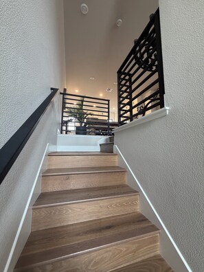 A staircase with wooden steps and black railings leading to a landing with a plant. - U.S. Open Retreat - Rooftop Condo Near Pebble Beach (Marina)