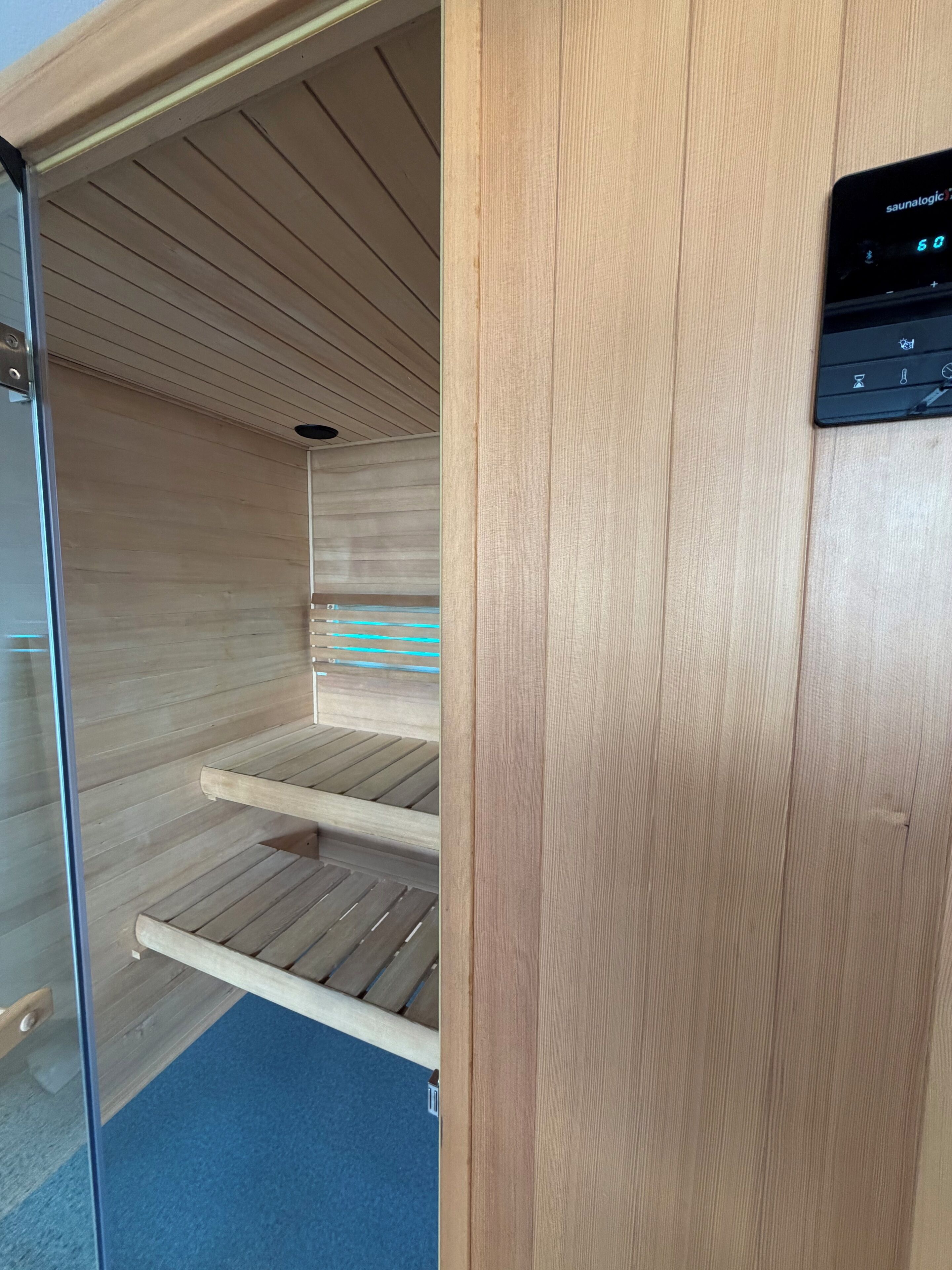 A sauna room with wooden benches and a control panel.