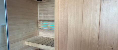 Una sala de sauna con bancos de madera y un panel de control.