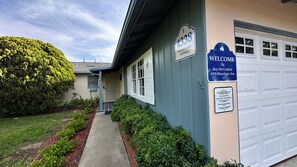 A residential property with a garage, a welcome sign, and a well-maintained garden. - Bay Ho Retreat—Sleeps 9—5-Minutes to La Jolla, Pacific Beach, Bay & Trolley (San Diego)