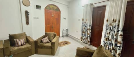 A living room with two sofas, a coffee table, and a door with curtains.