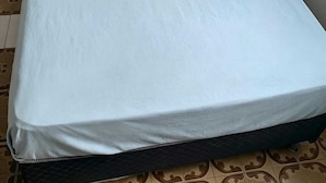 A single bed with a plain light-colored mattress and two pillows.