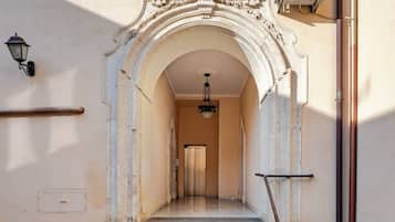 Una entrada imponente con un arco decorativo, una escalera que conduce a un segundo piso y un equipo de aire acondicionado de gran tamaño en la pared.