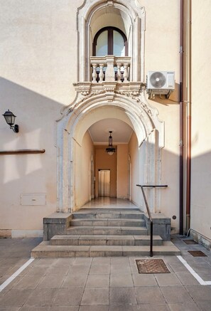 Una entrada imponente con un arco decorativo, una escalera que conduce a un segundo piso y un equipo de aire acondicionado de gran tamaño en la pared.