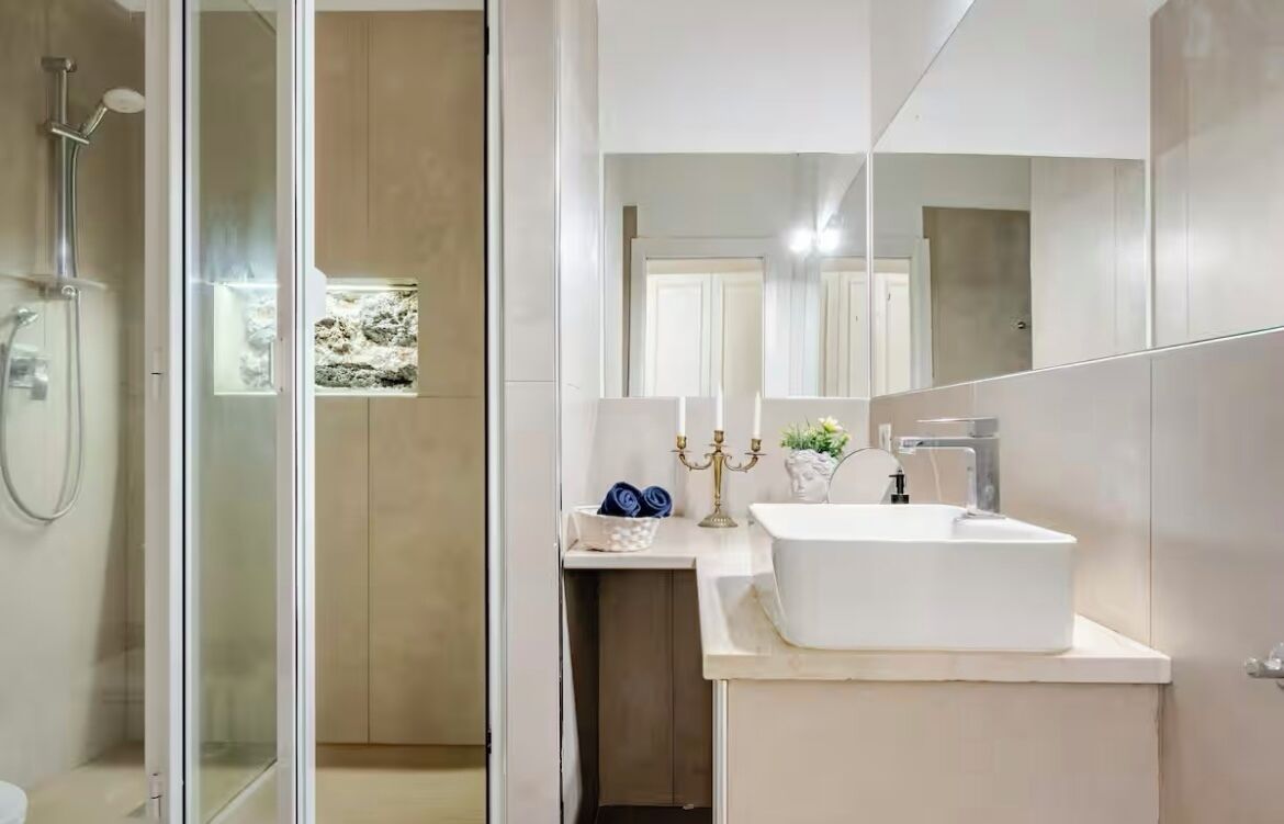 Un baño moderno con cabina de ducha de vidrio, un lavabo blanco y un espejo.