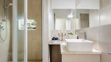 Un baño moderno con cabina de ducha de vidrio, un lavabo blanco y un espejo.