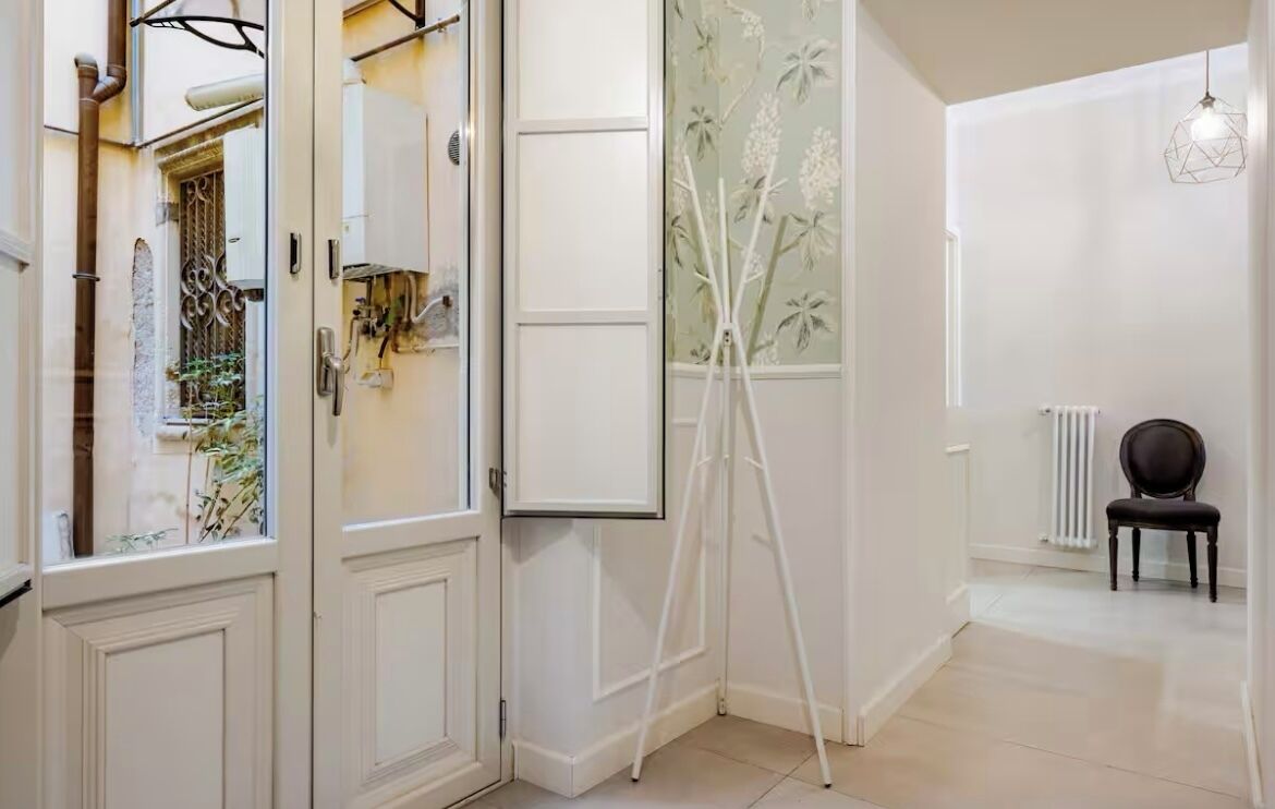 A hallway with a white door, a tripod, a radiator, and a chair.