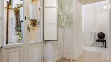 A hallway with a white door, a tripod, a radiator, and a chair.