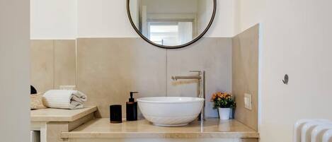 A bathroom with a white sink, a round mirror, and a towel on the counter.