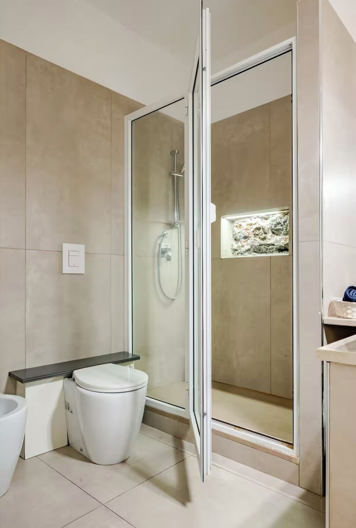 A modern bathroom with a glass-enclosed shower, a toilet, and a bidet.