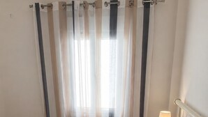Un letto con una coperta a motivi, asciugamani arrotolati e una lampada da comodino.