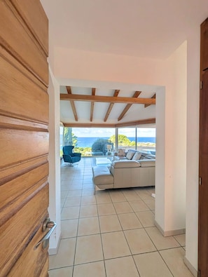 A spacious living area with a view of the sea, a wooden door, and a tiled floor. - New Listing: Villa with Pool - Ocean View - Marine Davia (Corbara)