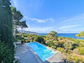 A swimming pool with a wooden deck, surrounded by greenery and overlooking a coastal landscape. - New Listing: Villa with Pool - Ocean View - Marine Davia (Corbara)